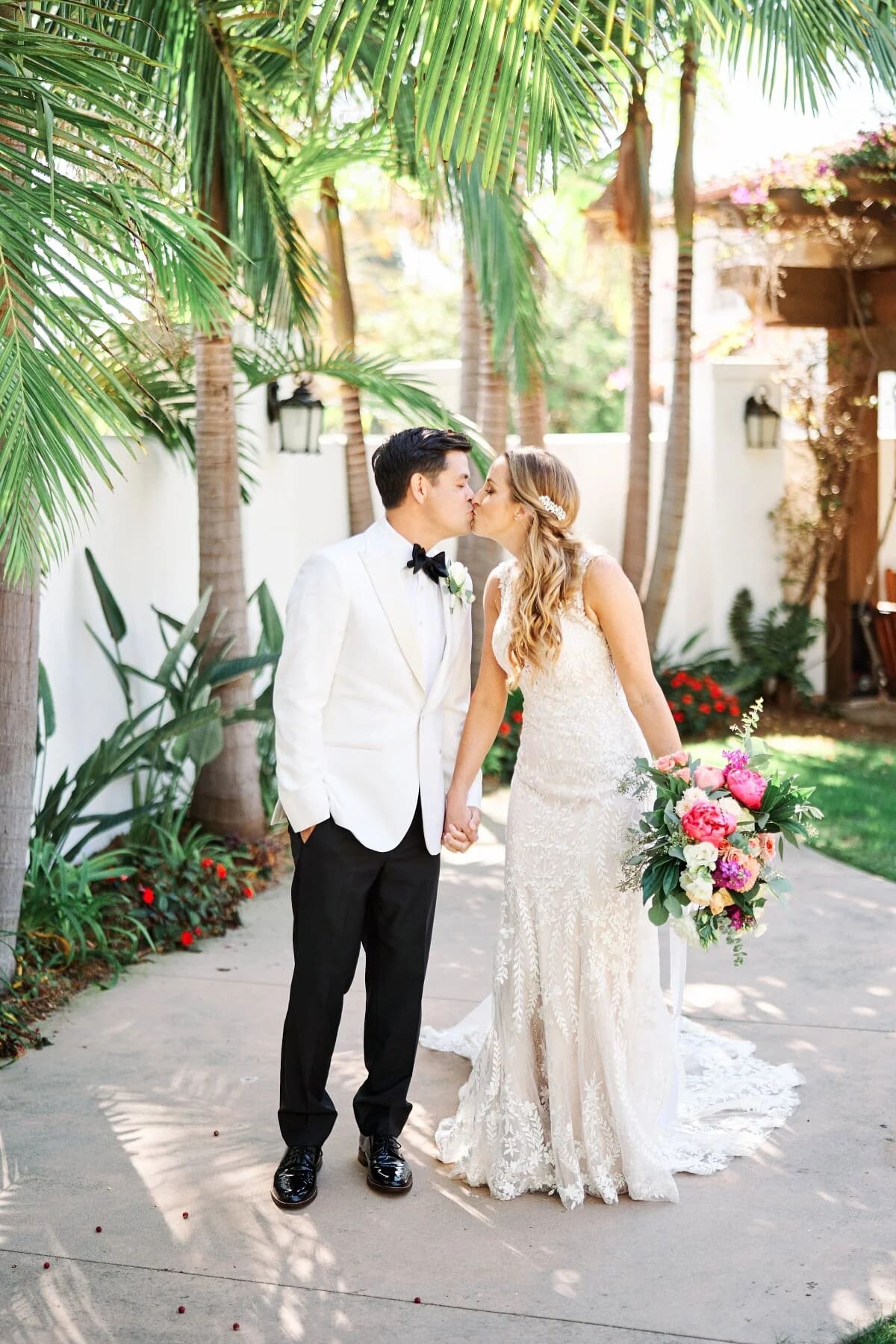 A bride and groom kissing under palm trees at Leo Carrillo Ranch.